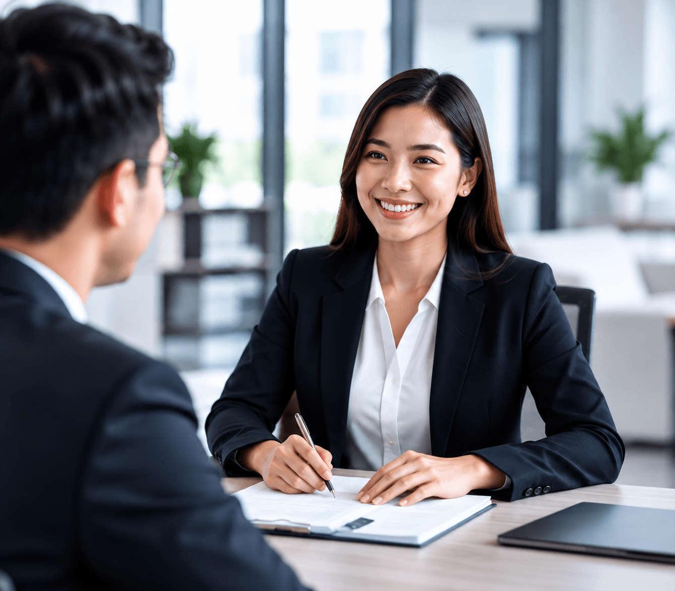 A professional meeting with a candidate across a desk in a bright office.